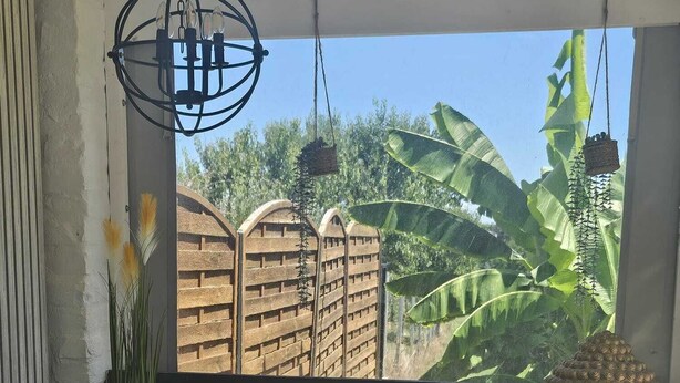 Una vasca idromassaggio con vista su una recinzione in legno e piante di banano.