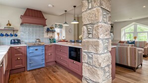 Una cocina con pared de piedra decorativa, armarios de madera y horno empotrado.
