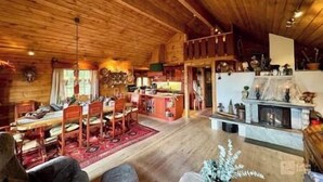 A spacious wooden cabin with a dining area, kitchen, and fireplace.