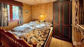 A wooden room with a bed, a cabinet, and a window.