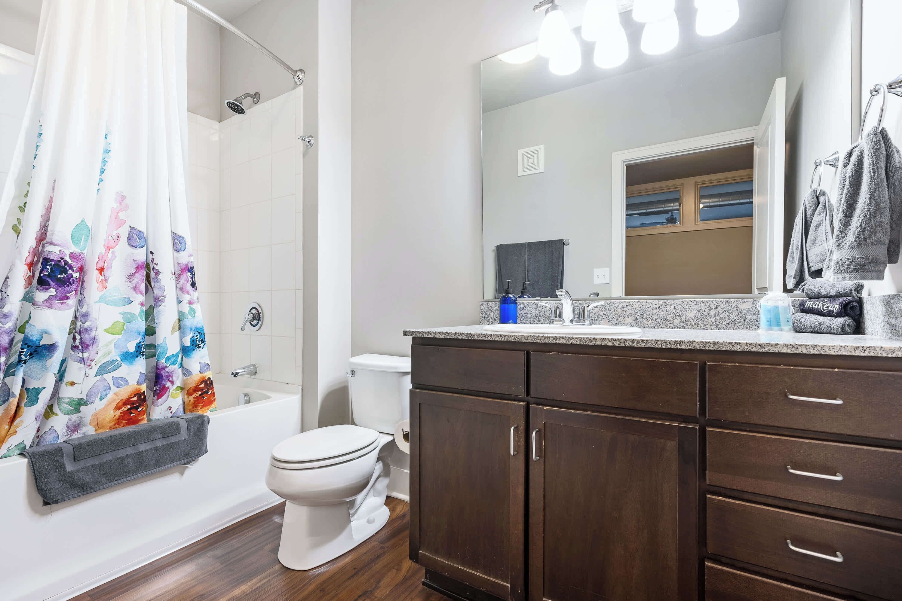Une salle de bain équipée d’une douche, de toilettes et d’un meuble-lavabo avec des tiroirs et un miroir.