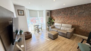 Un salon moderne avec un mur en briques, un canapé, une table basse et un téléviseur.