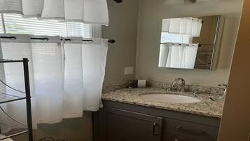 A bathroom with a sink, mirror, towel rack, and shower curtain.