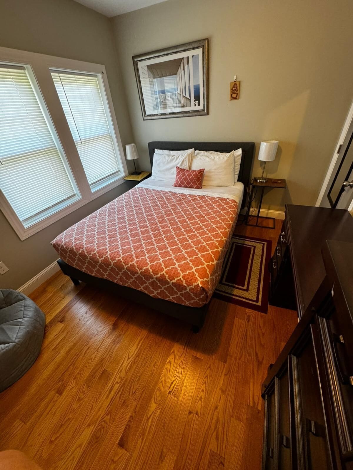 A bedroom with a large bed, two bedside lamps, a rug, a chair, and a dresser.