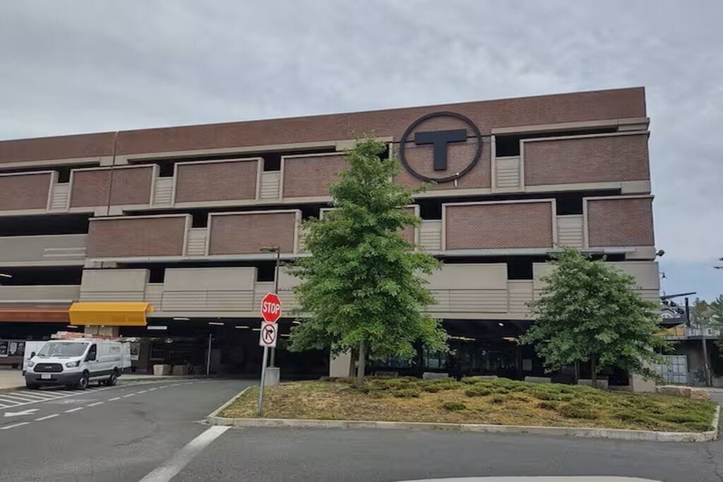 A multi-story parking garage with a 'T' logo, a stop sign, and a no parking sign.