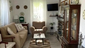 A living room with a beige sofa, a wooden coffee table, a patterned rug, a television, and a cabinet with glass doors. - Crosa Rosella (Bardineto)