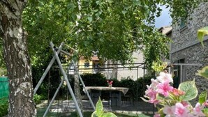 A tree-lined outdoor area with a swing set and a table with flowers. - Crosa Rosella (Bardineto)