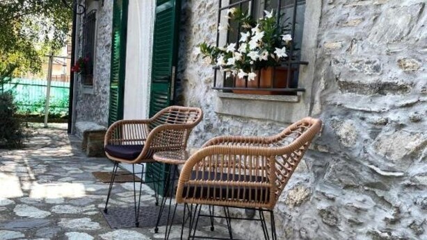 Wicker chairs outside a stone building with a window displaying white flowers. - Crosa Rosella (Bardineto)