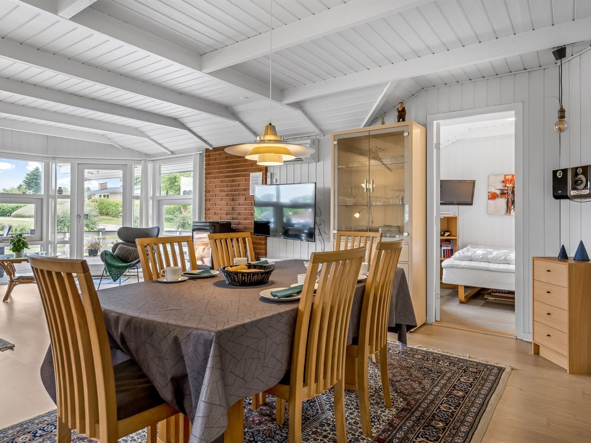 Un vaste espace dédié à la salle à manger, avec une grande table, des chaises en bois et un luminaire suspendu au design moderne.