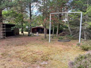 A backyard with a swing set, a wooden shed, and a small cabin.