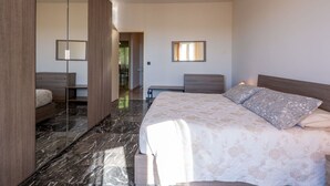 Un dormitorio moderno con una cama grande, una mesita de noche, un espejo y una lámpara en el techo.