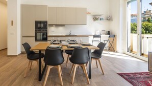 Cocina moderna con comedor, que incluye una mesa de madera, sillas negras y un ventanal con vistas a la ciudad.