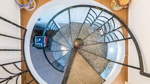 Una escalera de caracol con barandilla de metal que desciende a un nivel inferior.