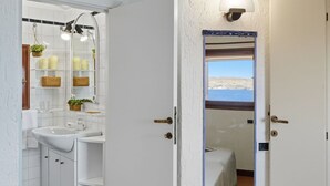Un baño con lavamanos, espejo y repisas con artículos de aseo.