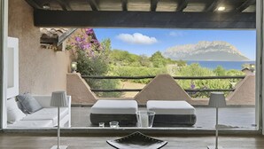 Une chambre moderne dotée d’un balcon offrant une vue panoramique sur la mer et les montagnes.