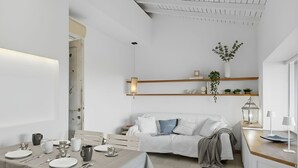 Un espace de vie moderne et minimaliste comprenant un coin repas, un canapé et une cuisine.