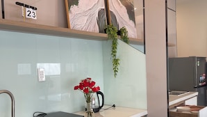 A modern kitchen with a built-in oven, a coffee maker, and a vase with red flowers on the countertop. - Unite StayCation Le Van Sy (Ho Chi Minh City)
