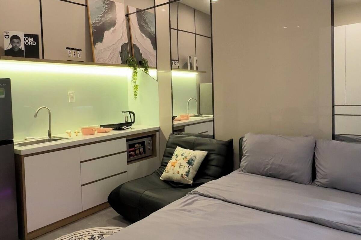 A modern bedroom with a bed, a desk, and a mirror.