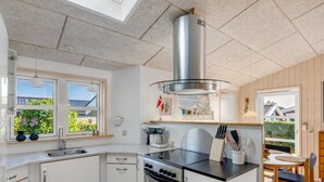 Une cuisine moderne dotée d’un îlot central, d’un four encastré et d’une fenêtre donnant sur un espace verdoyant.