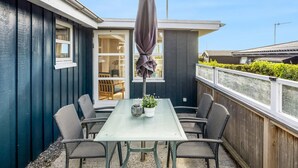 Une terrasse avec une table et des chaises, un parasol et une vue sur le ciel.