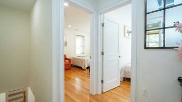 Ein Flur, der zu einem Schlafzimmer mit Bett, Sessel und Fenster führt.
