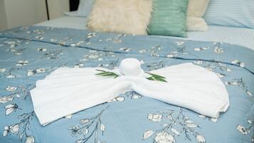 Ein ordentlich bezogenes Bett mit einer blau karierten Tagesdecke und einem dazwischen gefalteten weißen Handtuch.
