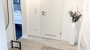 A hallway with a patterned rug, a white door, and a small plant. - Beautiful Apartment | Cologne | 15 min. Phantasialand (Hürth)