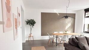 A modern dining area with a wooden table, white chairs, and a large abstract painting on the wall. - Beautiful Apartment | Cologne | 15 min. Phantasialand (Hürth)