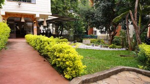 A pathway leading to a building with a covered entrance, surrounded by well-maintained hedges and greenery. - ZZZ Hostel & Restaurant  (Nairobi)