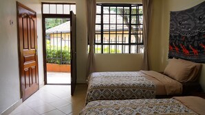 A hotel room with two beds, a balcony, and a view of the outside. - ZZZ Hostel & Restaurant  (Nairobi)