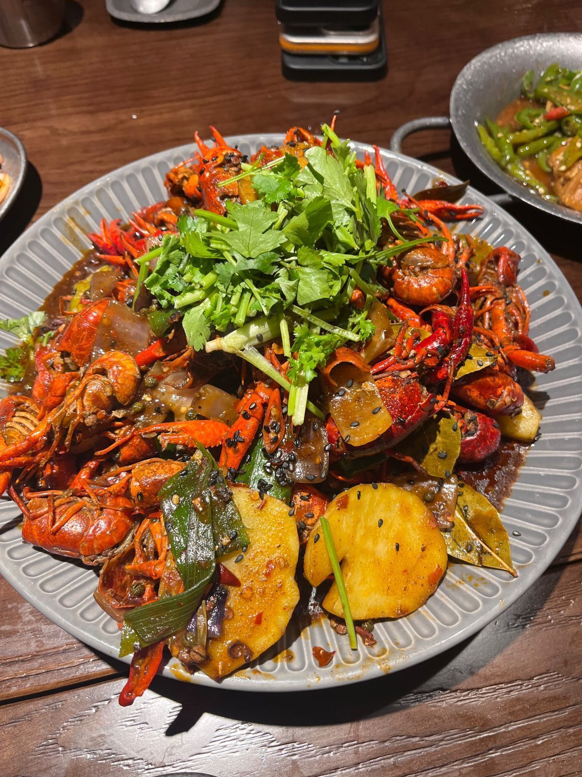 Un plato de crawfish cocidos con verduras y hierbas.