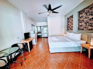 A hotel room with a bed, desk, chair, ceiling fan, and a view of the outside. - Superior King Room with Sofa & Balcony (Muang Pattaya)