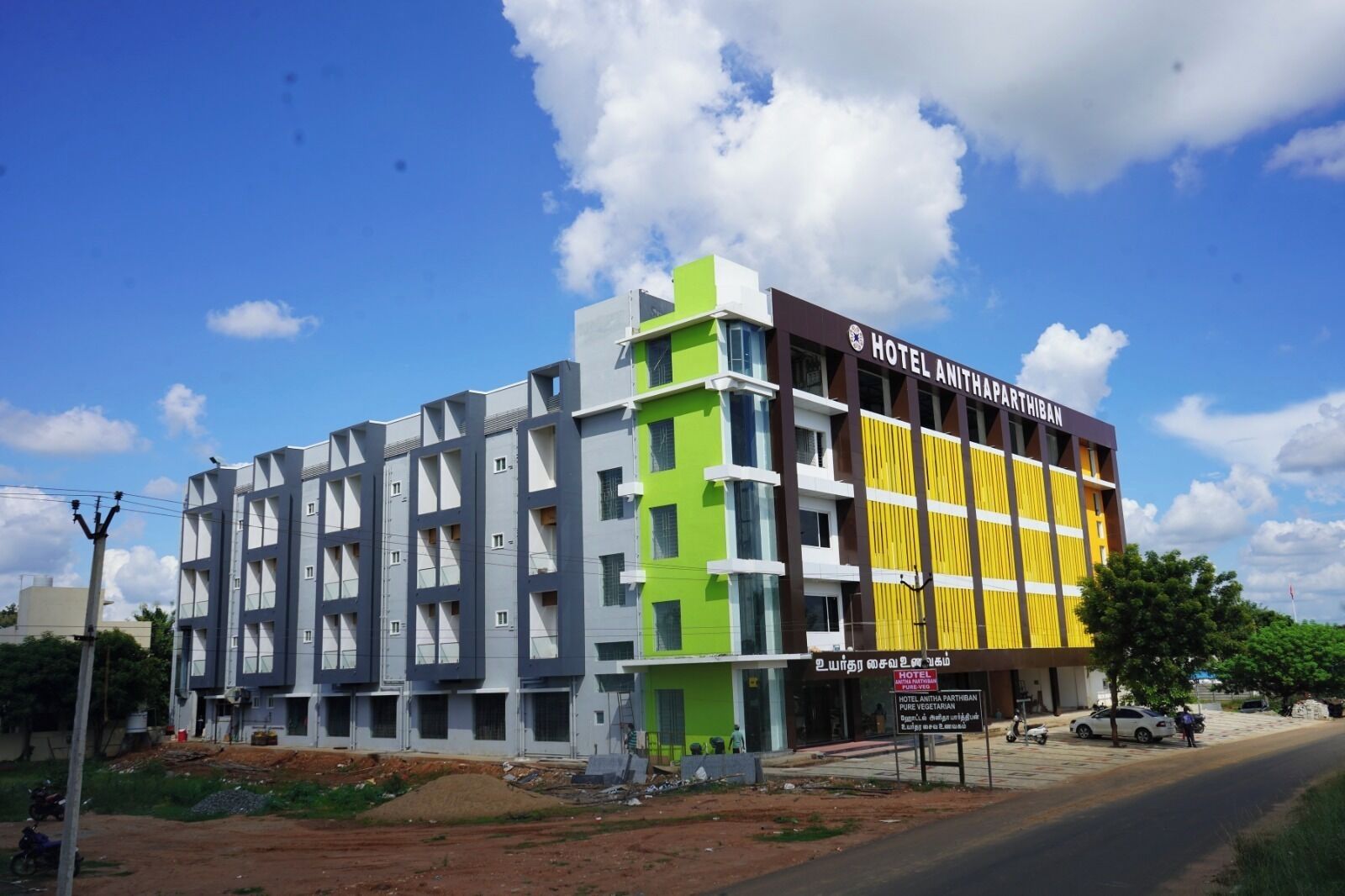 Un hôtel à plusieurs étages au design moderne, dont la façade présente un mélange de couleurs : gris, vert et jaune.