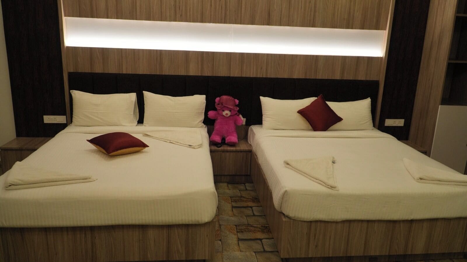 Ein Hotelzimmer mit zwei Betten, jeweils mit einem Kopfkissen und einem gefalteten Handtuch.
