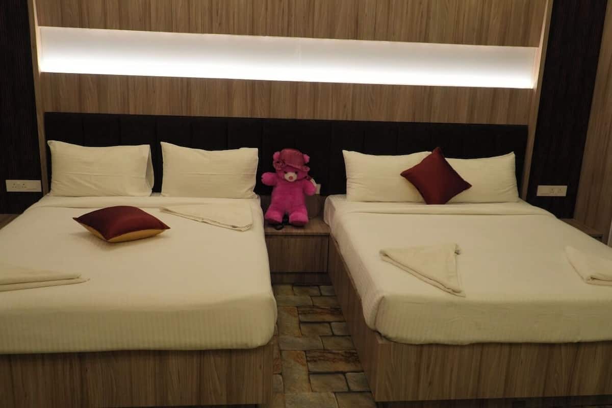 A hotel room with two beds, each with a pillow and a folded towel.
