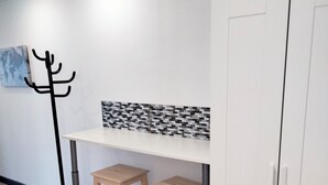 Ein Zimmer mit einem weißen Kleiderschrank, einem Kleiderständer und einem Tisch mit zwei Hocker.