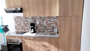 Eine moderne Küche mit Holzausstattung, einer Steinrückwand, einer Kaffeemaschine und einem schwarzen Tisch mit Drahtkorb.