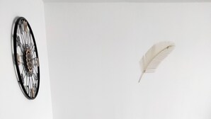 Ein runder Tisch mit vier Stühlen, einer Zierfeder und einer Wanduhr.