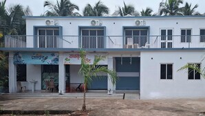 Un edificio de dos pisos con balcón, unidades de aire acondicionado y un letrero.