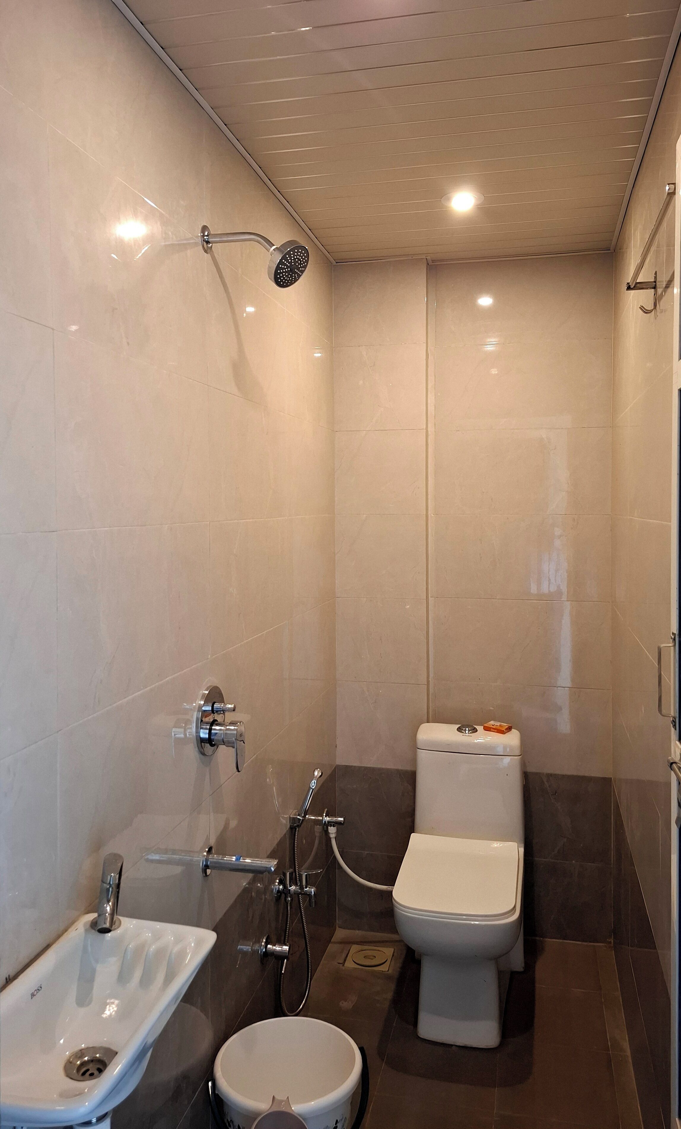 Un baño pequeño y moderno con ducha, inodoro y lavamanos.
