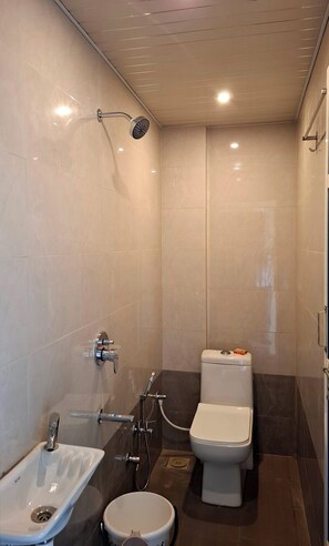 A small, modern bathroom with a shower, toilet, and sink.