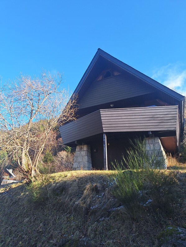 A modern house with a sloped roof, a stone foundation, and a garage.