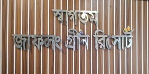 A decorative metal sign with text and a butterfly, mounted on a striped wooden background. - Jaflong Green Resort (Gowainghat)