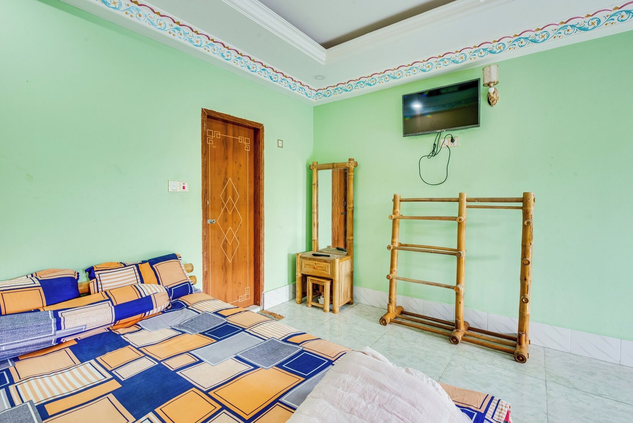 Una habitación con una cama, una escalera de madera, un espejo y un televisor en la pared.