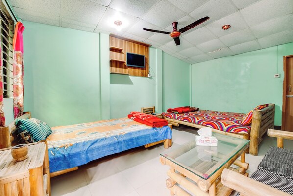 A room with two wooden beds, a glass table, and a ceiling fan. - Jaflong Green Resort (Gowainghat)