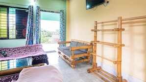 A room with a bed, a sofa, a TV, and a window with curtains.