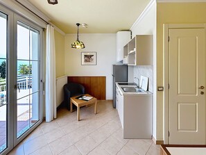 A compact kitchen with a refrigerator, sink, and a dining area with a table and chair.