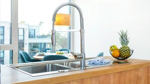 Uma cozinha moderna com uma pia de aço inoxidável, bancada de madeira e uma tigela de frutas.