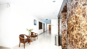 A hotel lobby with a marble reception desk, wooden chairs, a vase with flowers, and a framed picture on the wall. - truego hotel (Phnom Penh)