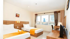 Een hotelkamer met twee bedden, een bureau, een stoel, een televisie en een raam met gordijnen.